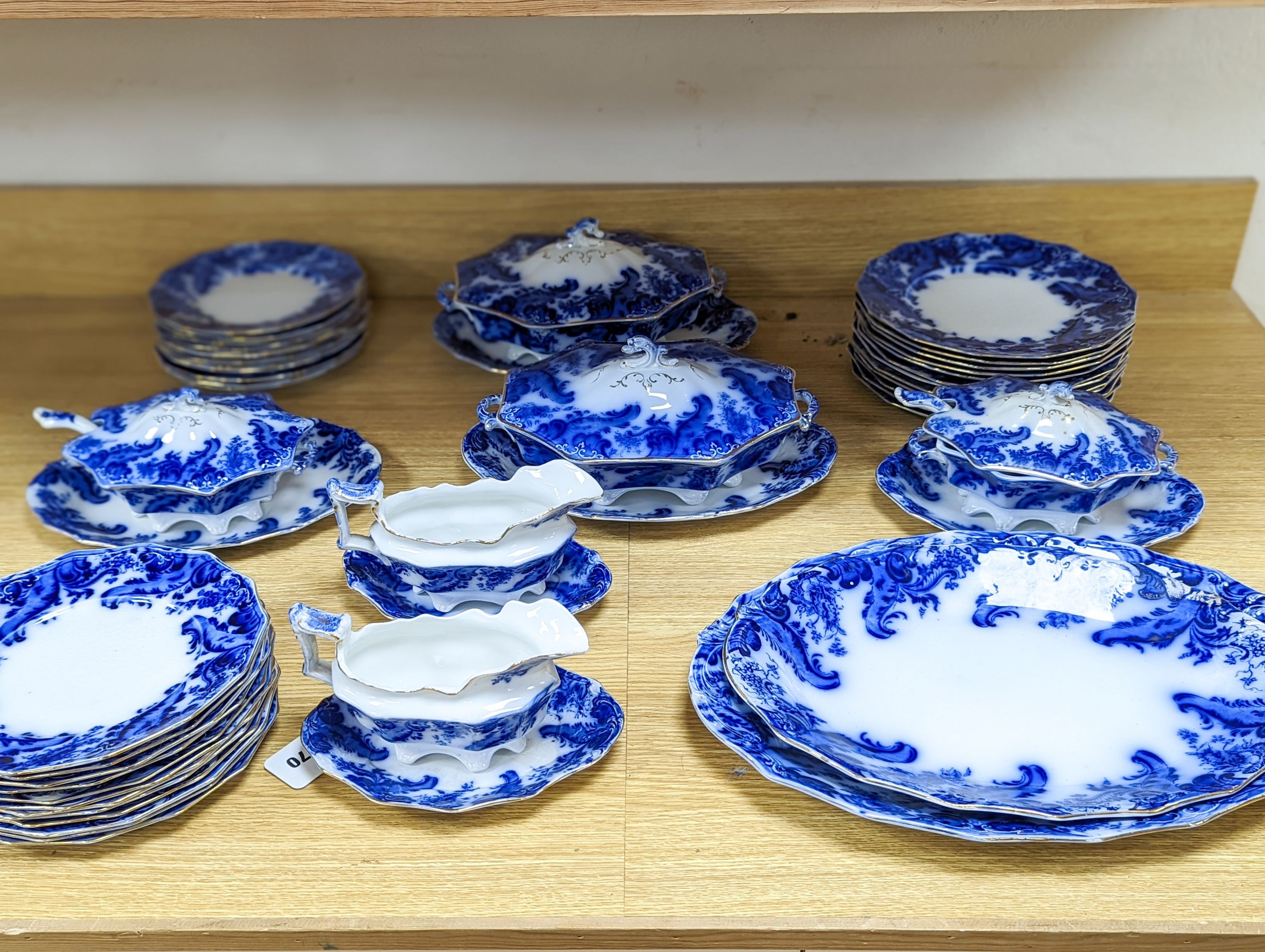 A W. H. Grindley Argyle pattern flow blue dinner service, c.1900 mostly for 12 place settings, two sauce tureens, covers and stands, two vegetable tureens and covers, two gravy boats, and six graduated meat dishes